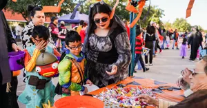 children dressed in costume choosing candy from a booth at Halloweentown event.