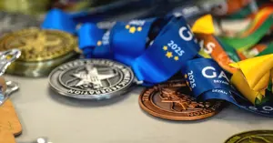 gold, silver and bronze winner's medals for the 2025 Games of Texas laid out on a table