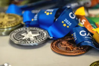 gold, silver and bronze winner's medals for the 2025 Games of Texas laid out on a table