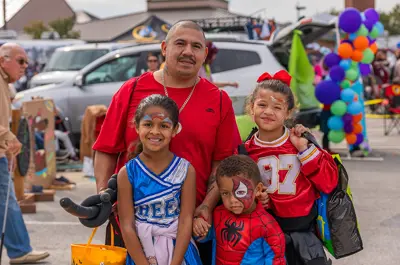 A family wearing costumes, including a cheerleader, football player and spiderman.
