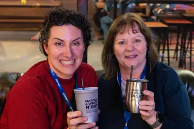 Two women hold Maroon and White Night cups.