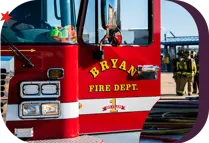Bryan Fire Department branded truck door with firefighters in the background wearing full gear