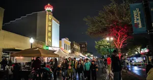 People walking through booths at First Friday with Christmas lights placed throughout downtown.