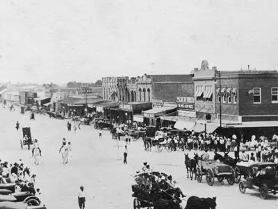 Black and white picture of Historic Downtown Bryan with horse-drawn carts and early automobiles.