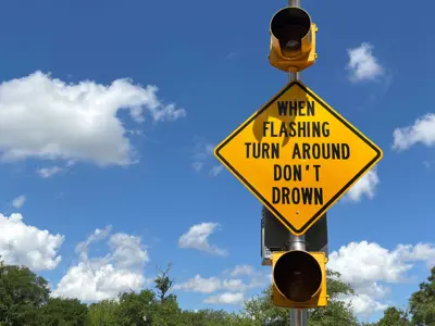 flashing roadway sign with text that says "When Flashing, Turn Around, Don't Drown"