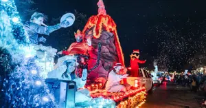 People in costume wave from a float during the Christmas parade.