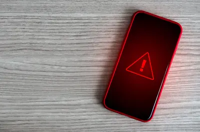 mobile phone laying on a table with an alert message icon displaying on the screen