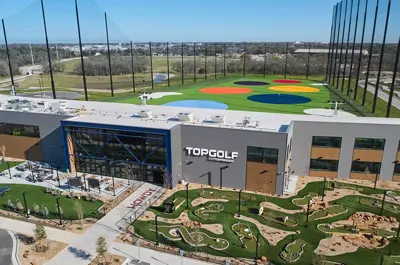 Aerial view of the TopGolf facility with minigolf course and colorful hitting range.