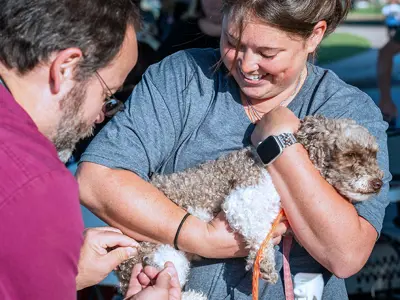 animal center staff administering vaccination to a dog being soothed