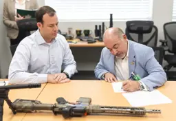 Mayor Bobby Gutierrez and Strategic Armory Corps President of the Board and Owner Jose Augusto Schincario signing a deed.