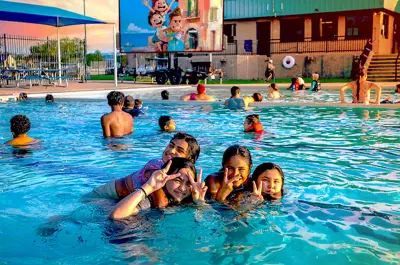 families having fun at the pool with a projected movie on a large screen in the background