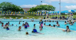 many families enjoying swimming in Bryan Aquatic Center's pool on a bright summer day