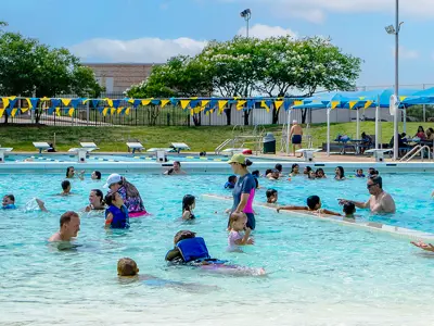 many families enjoying swimming in Bryan Aquatic Center's pool on a bright summer day