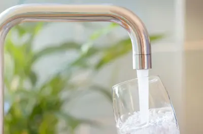 water faucet in a home pouring water into a glass