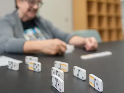 group of dominoes stacked with an elderly woman playing her turn