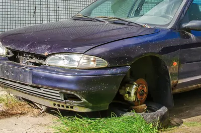 broken down car resting on blocks, rusted and non functional