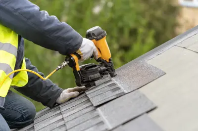 Roofer using a nail gun to nail down shingles.