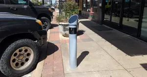 monitoring device mounted on a concrete pole near the curb of downtown Bryan street near parked cars.