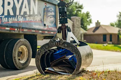 waste truck arm picking up bulky trash from the curb