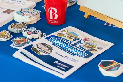 A table of open house flyers and City of Bryan stickers.