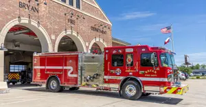 side view of the new 2026 Bryan Fire Department fire truck in front of the station, including hose hookup equipment