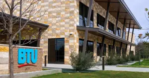 Brick sign with colorful BTU logo in front of the new BTU facility building in the background.