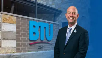Gary Miller smiling in front of the BTU admin building front entrance