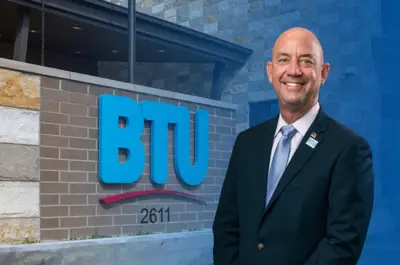 Gary Miller smiling in front of the BTU admin building front entrance