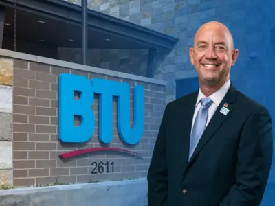 Gary Miller smiling in front of the BTU admin building front entrance