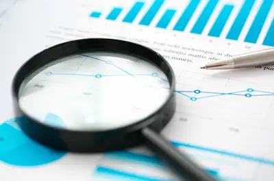 magnifying glass and pen laying over financial report paperwork