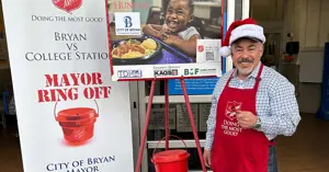 Mayor Bobby Gutierrez ringing a bell in front of a Salvation Army donation stand.