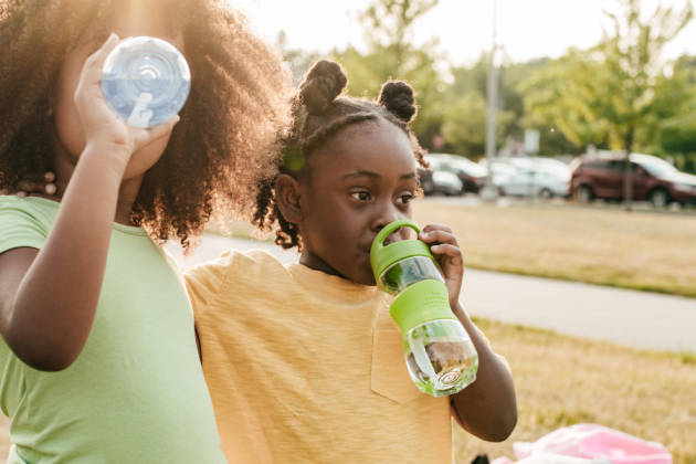 Photo of two girls drinking from water bottles.