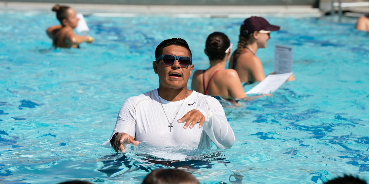 Photo of a swim instructor in the pool at the Bryan Aquatic Center wearing sunglasses.