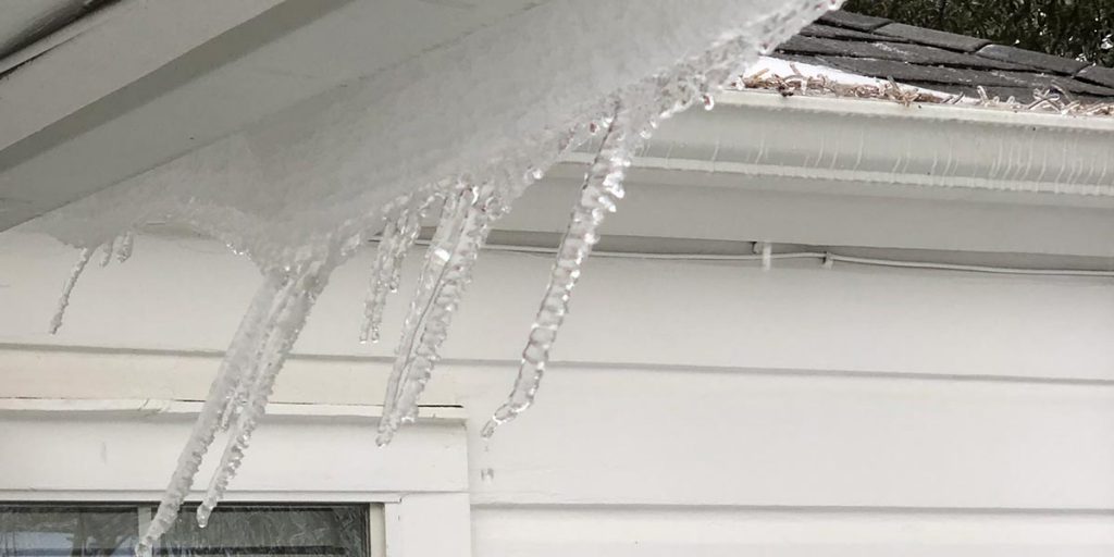 ice dam on a roof gutter with icicles