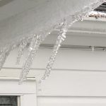ice dam on a roof gutter with icicles