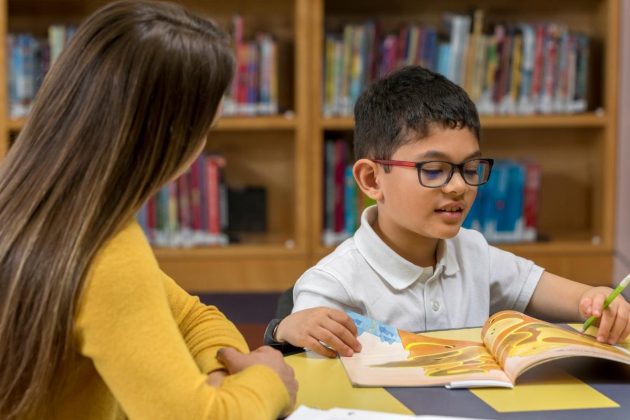 Photo of a young student being tutored by a high school student.