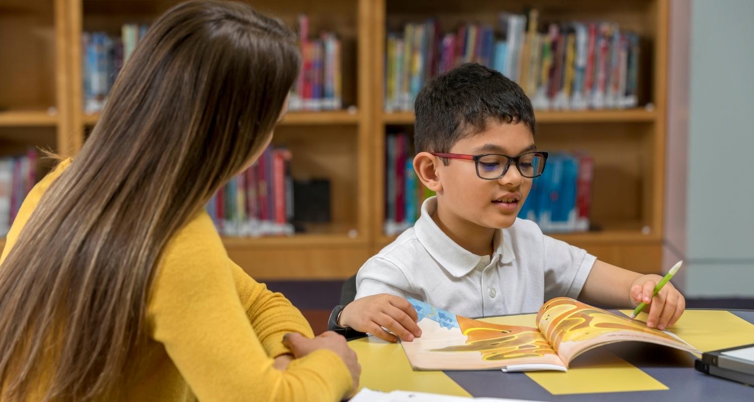 Photo of a young student being tutored by a high school student.