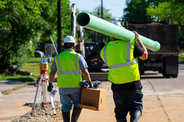 Wastewater workers carrying a new sewer pipe.