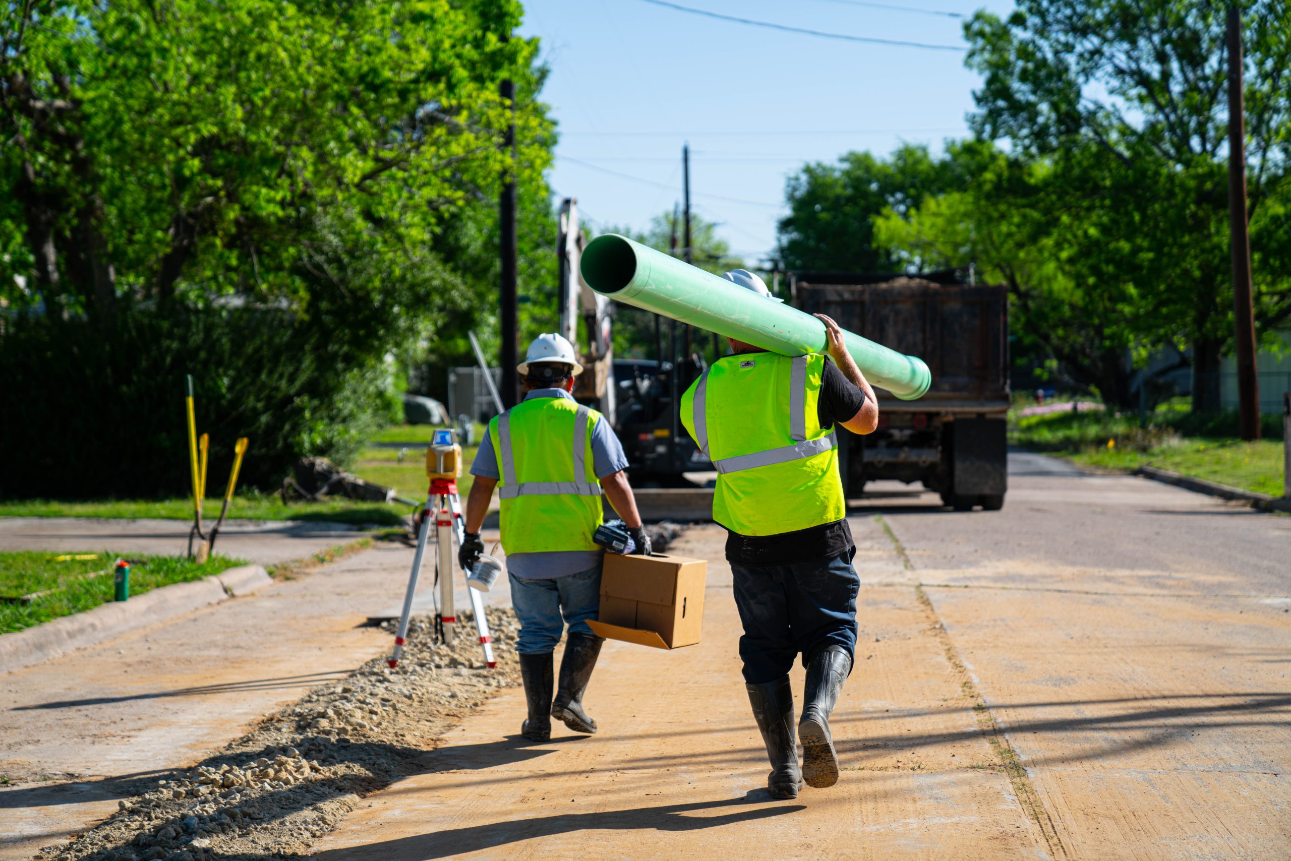 Wastewater workers carrying a new sewer pipe.