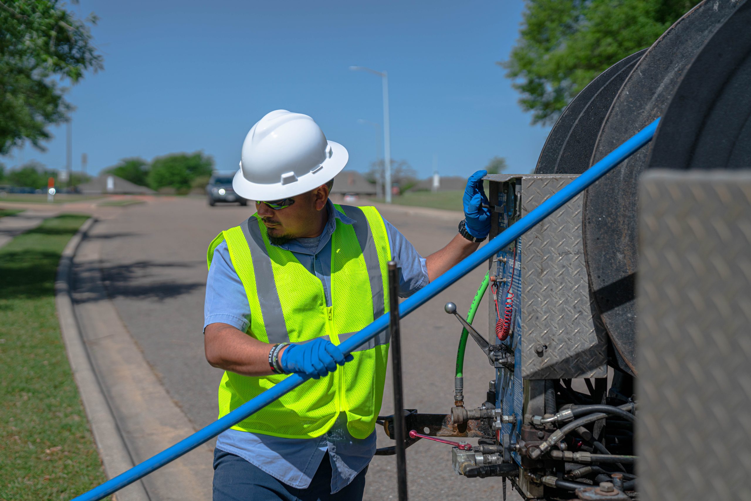 Wastewater worker managing the vacuum truck to clean a sewer pipe.