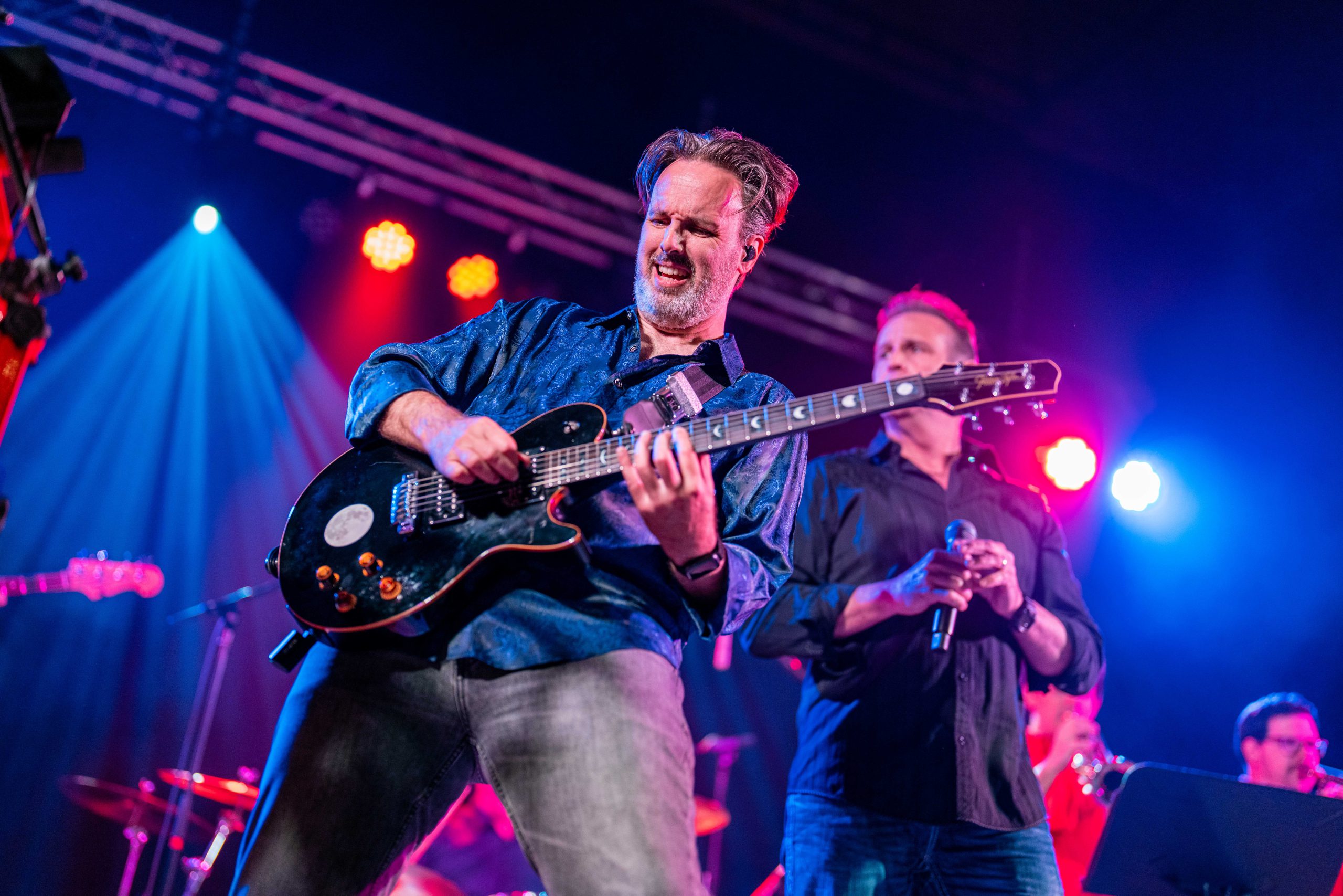 Man plays electric guitar on stage.