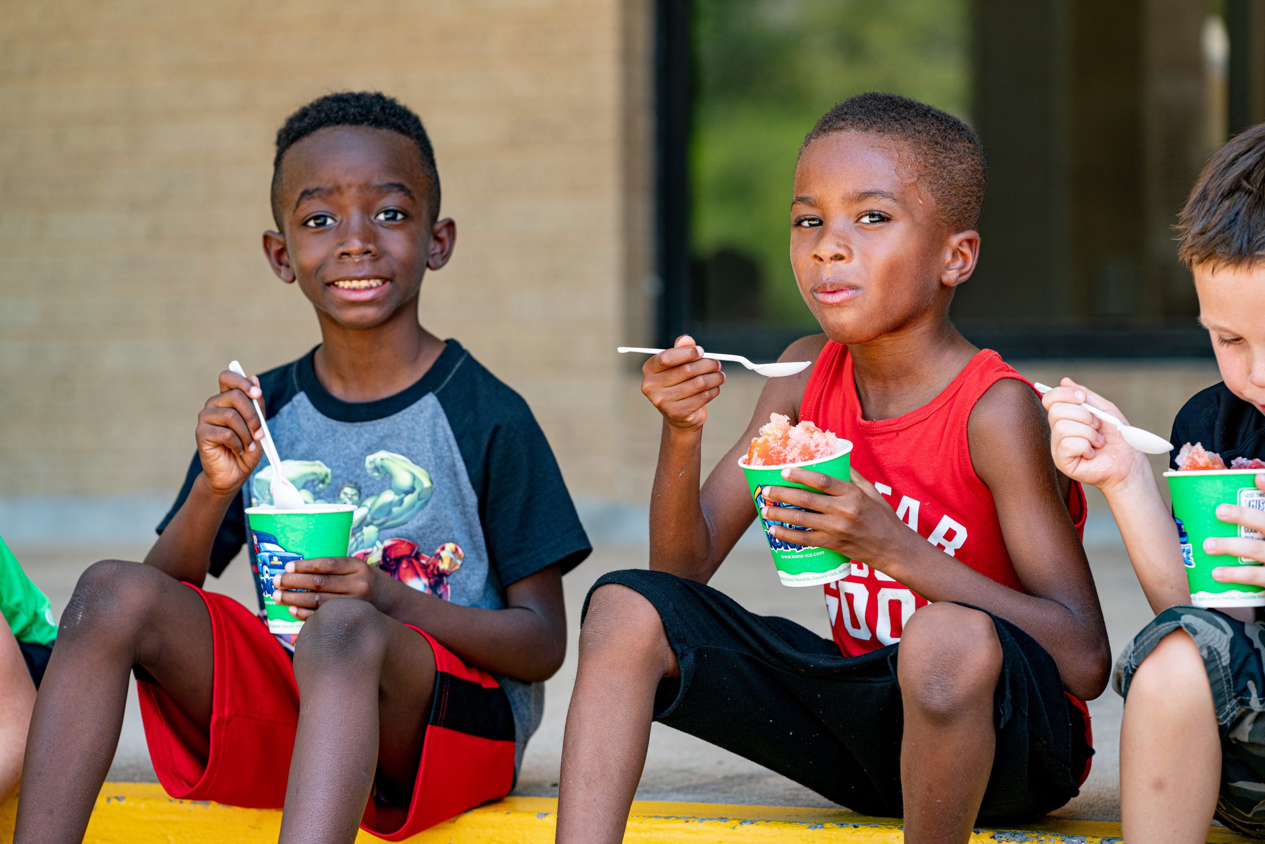 Two boys sitting eating snow-cones