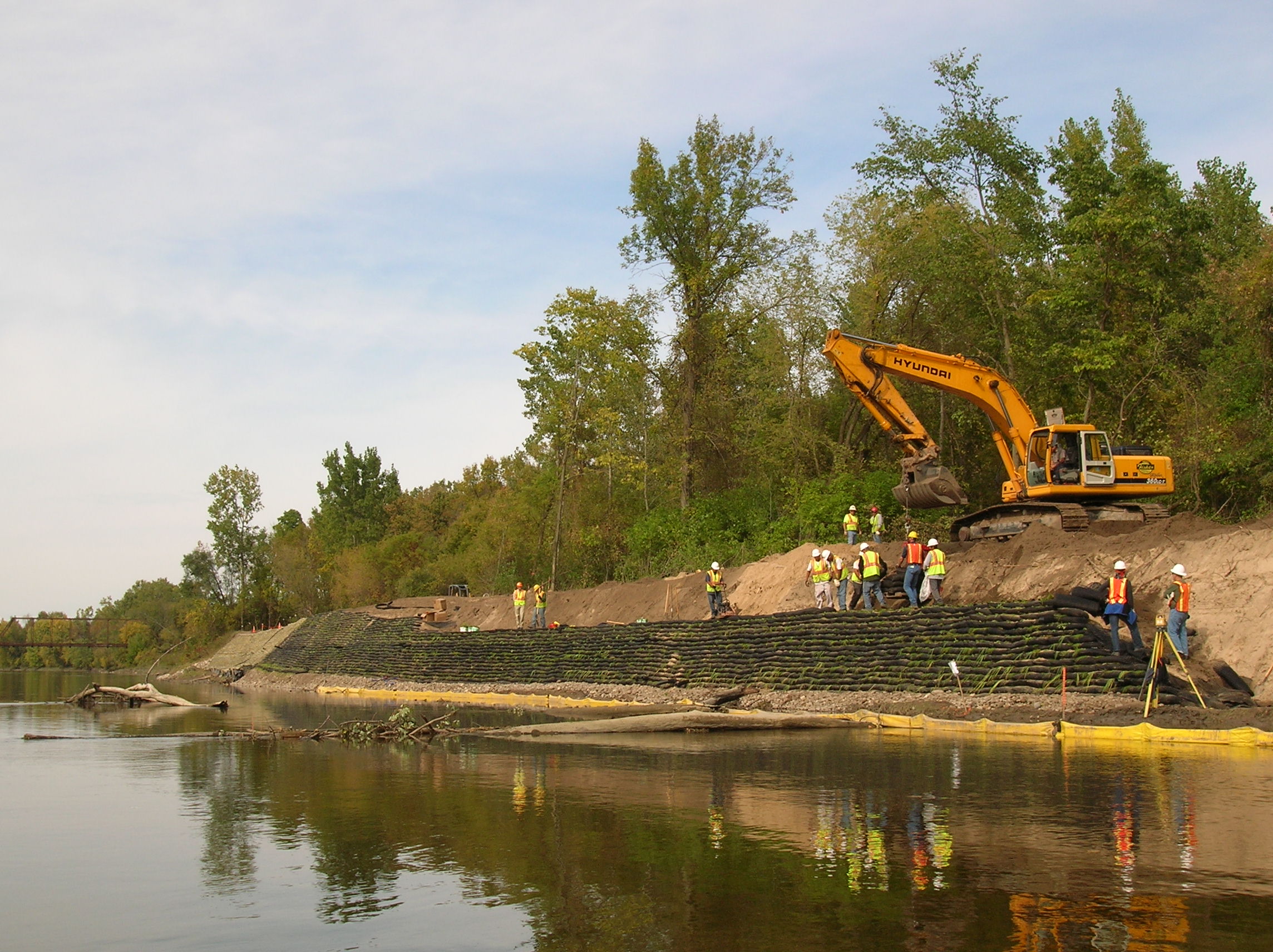 Photo of construction crews installing geobags along a bank of a river.