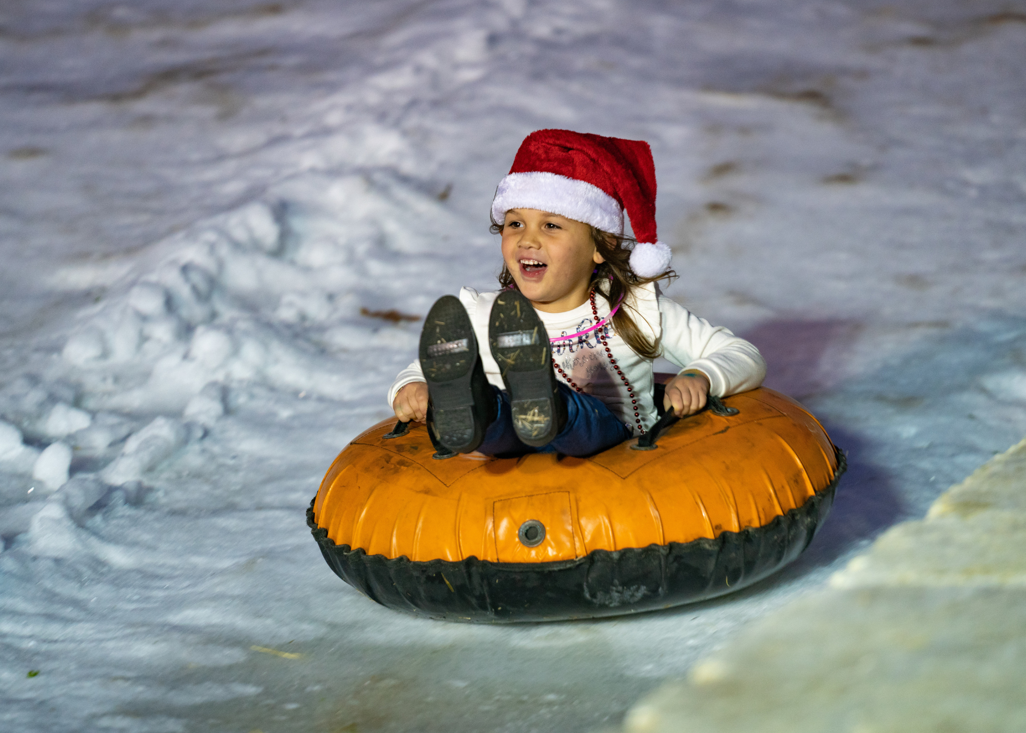 Photo of a girl sliding down a snow hill at Holiday Magic