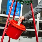 Photo of person putting money in the Salvation Army red Kettle.