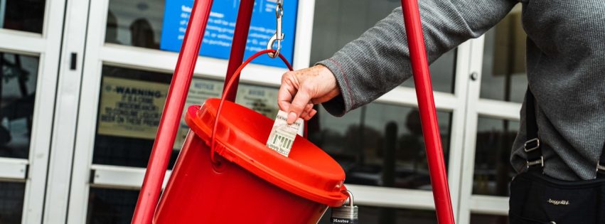 Photo of person putting money in the Salvation Army red Kettle.