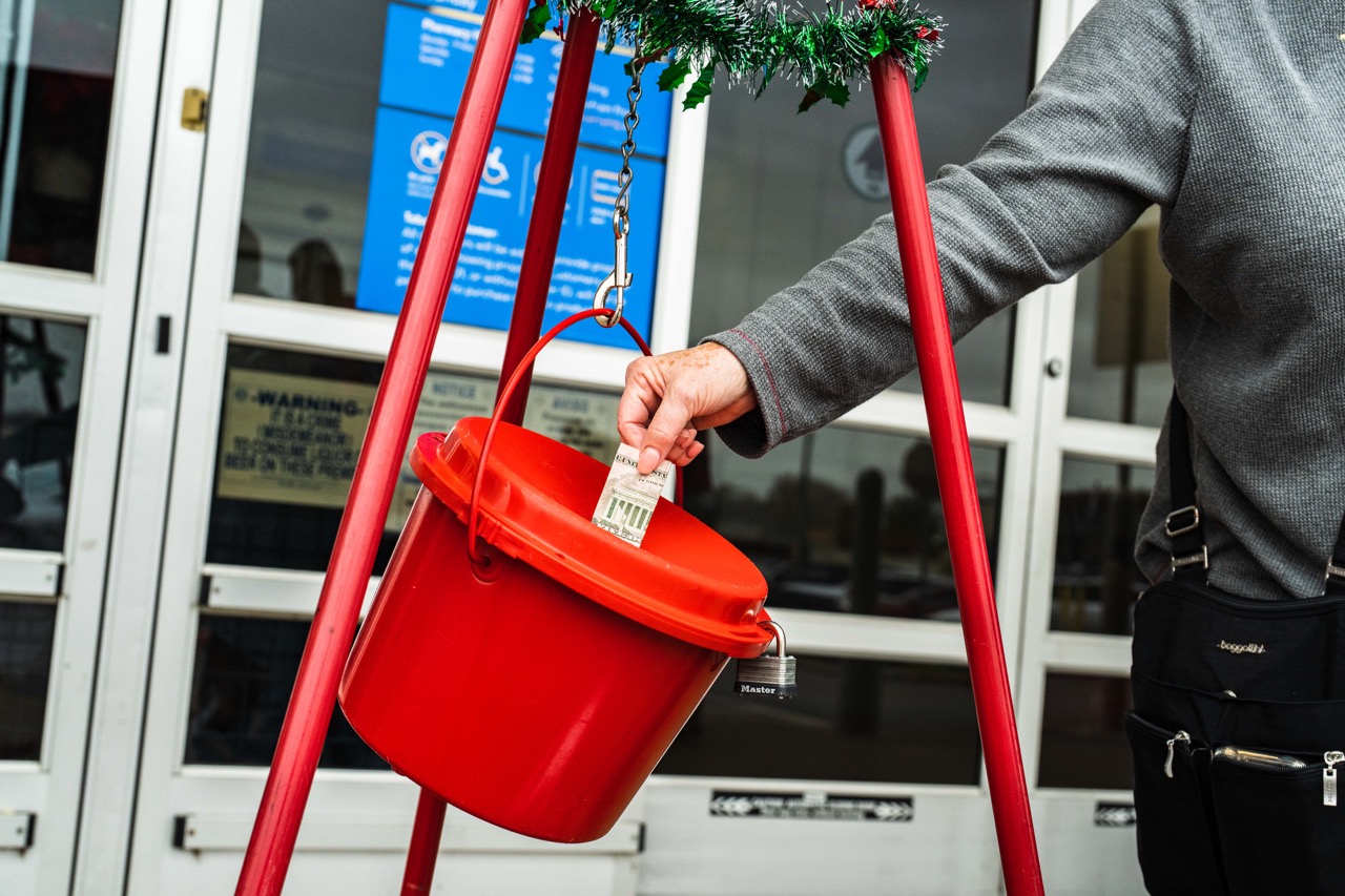 Photo of person putting money in the Salvation Army red Kettle. 