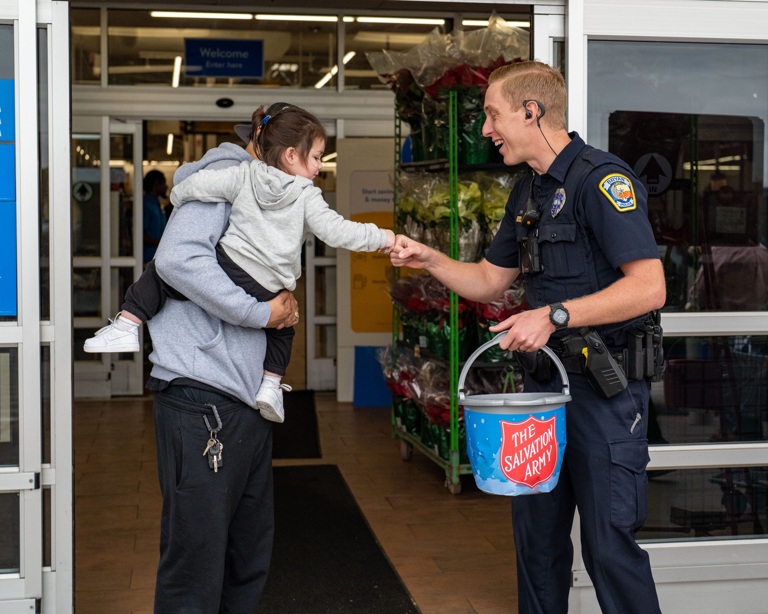 Photo of a Bryan Police Officer giving a little girl a fist bump at the Salvation Army Mayor Ring Off