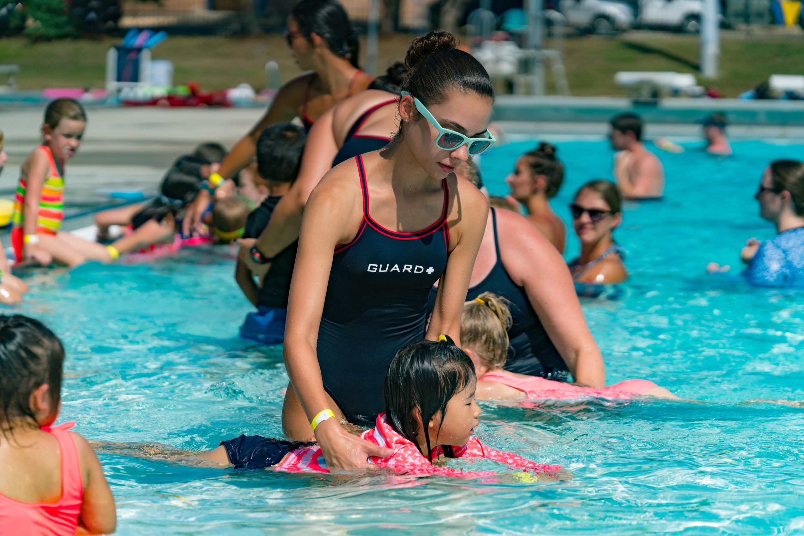 Swim instructor assisting a little girl learning how to swim.