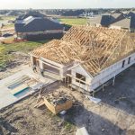 Drone photo of a house being constructed with workers walking up.